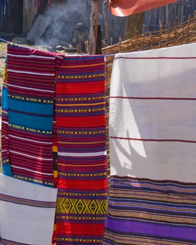 Striped and white handwoven cloths hanging in the sun