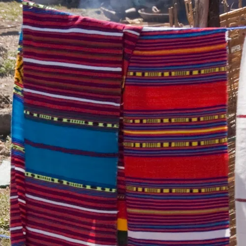 Handwoven cotton cloths in red, cobalt and violet stripes, hanging on a line